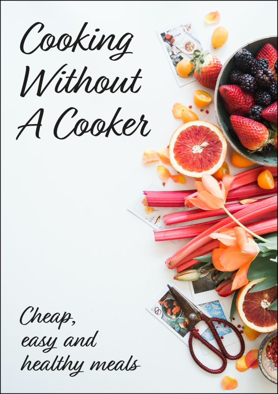 A book cover displaying the text "Cooking Without A Cooker" and the image of a bowel of fruit with other fruits surrounding it